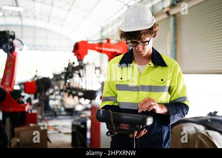 engineer checking control panel and teaching new Automatics robot arm and operating control machine in factory. Stock Photo