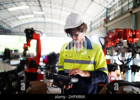 engineer checking control panel and teaching new Automatics robot arm and operating control machine in factory. Stock Photo