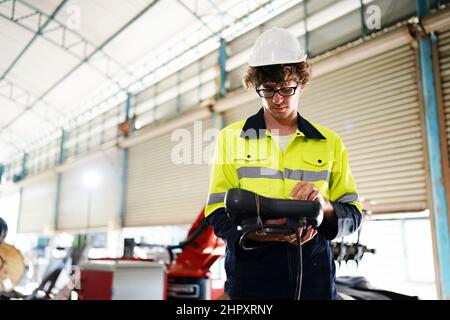 engineer checking control panel and teaching new Automatics robot arm and operating control machine in factory. Stock Photo