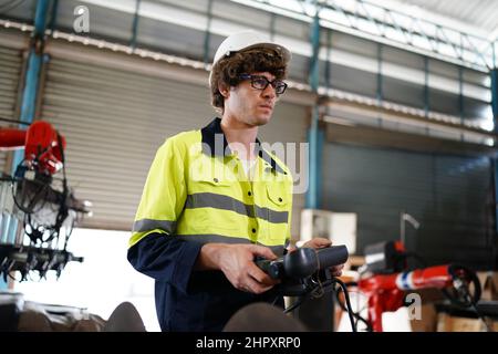 engineer checking control panel and teaching new Automatics robot arm and operating control machine in factory. Stock Photo