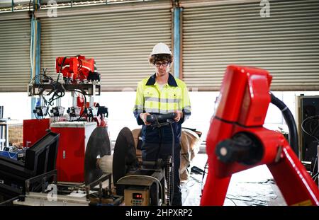 engineer checking control panel and teaching new Automatics robot arm and operating control machine in factory. Stock Photo