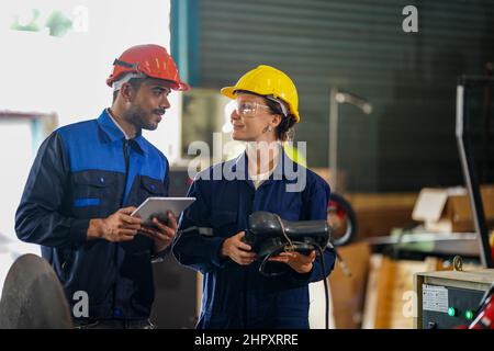engineer checking control panel and teaching new Automatics robot arm and operating control machine in factory. Stock Photo