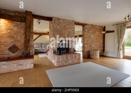 Weston Colville, Cambridgeshire - Feb 13 2018: Furnished living room hallway with exposed timber floors, seating in background and inglenook fireplace Stock Photo