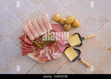 top view of raw cheese in skillet and charcuterie on tiled table Stock Photo