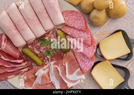 top view of raw cheese in skillet and charcuterie on tiled table Stock Photo