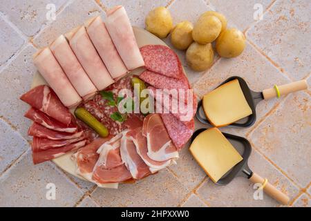 top view of raw cheese in skillet and charcuterie on tiled table Stock Photo