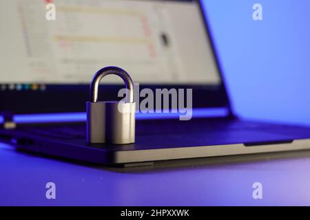 Locked metal padlock on a laptop keyboard over blue background. Cyber security, antivirus software concept. Stock Photo
