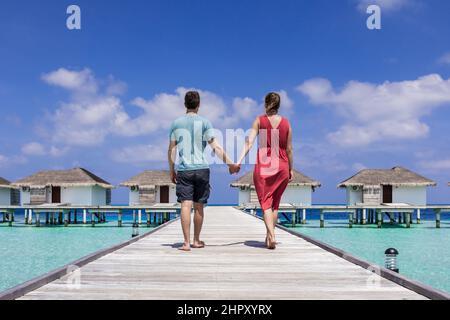 Couple spending romantic beach vacation holidays at luxurious resort in Maldives with overwater villas, turquoise sea water and blue sky. Paradise ato Stock Photo