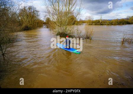 A man on a paddleboard makes his way along the flooded Ferry Lane at Uckinghall, near Tewkesbury, Gloucestershire, as parts of the UK face heavy snow, strong winds and lightning strikes, while a severe flood warning is still in place. The Environment Agency is urging communities in parts of the West Midlands and Yorkshire, especially those along the Rivers Severn and Ouse, to be prepared for significant flooding following high rainfall from Storm Franklin. Picture date: Thursday February 24, 2022. Stock Photo