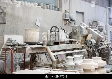 Various clay constructions placed near production machine in light marble workshop with gray walls Stock Photo