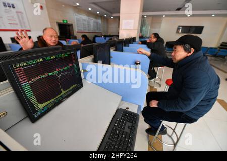 Fuyang, China. 24th Feb, 2022. Two investors talk about the stock exchange flow with monitors showing the Shanghai Composite Index. Under the influence of the Russia-Ukraine war, China's A-share market once saw panic transactions. The turnover of the two markets soon exceeded one trillion yuan, and by the end of the trading volume exceeded 1.3 trillion yuan, A 5-month high. By the end of trading, the Shanghai Index was at 3429 points, down 1.7 percent, the Shenzhen Index at 13252 points, down 2.2 percent, gem index at 2783 points, down 2.11 percent. Credit: SOPA Images Limited/Alamy Live News Stock Photo