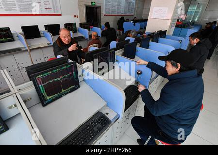 Fuyang, China. 24th Feb, 2022. Two investors talk about the stock exchange flow with monitors showing the Shanghai Composite Index. Under the influence of the Russia-Ukraine war, China's A-share market once saw panic transactions. The turnover of the two markets soon exceeded one trillion yuan, and by the end of the trading volume exceeded 1.3 trillion yuan, A 5-month high. By the end of trading, the Shanghai Index was at 3429 points, down 1.7 percent, the Shenzhen Index at 13252 points, down 2.2 percent, gem index at 2783 points, down 2.11 percent. Credit: SOPA Images Limited/Alamy Live News Stock Photo