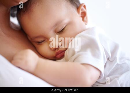 Shes got an off the chart cuteness score. Closeup of a baby girl sleeping in her mothers arms. Stock Photo