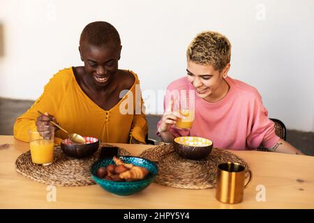 Multiethnic female couple relaxing at home while having breakfast Stock Photo