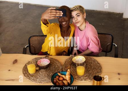 Happy multiethnic couple taking a selfie while having dinner Stock Photo