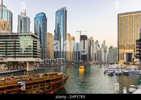 Tourists can enjoy a traditional dhow boat cruise along the modern Dubai Marina, surrounded by luxury living skyscrapers, restaurants and yacht clubs. Stock Photo
