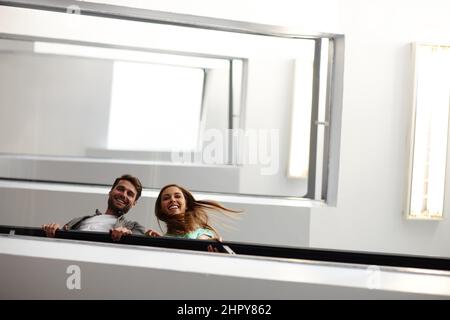 Were making our way to the top. Shot of two people in stairwell smiling while looking down at you. Stock Photo