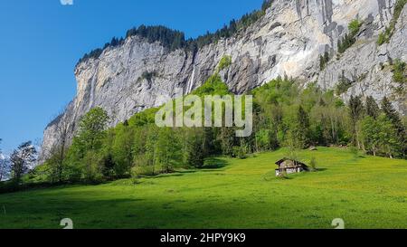A wooden hut overlooked by cliffs in the Lauterbrunnen Valley, Switzerland Stock Photo