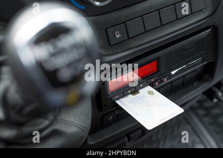 A blurred shot of a gear shifter in the background of a digital tachograph from an angle. Stock Photo