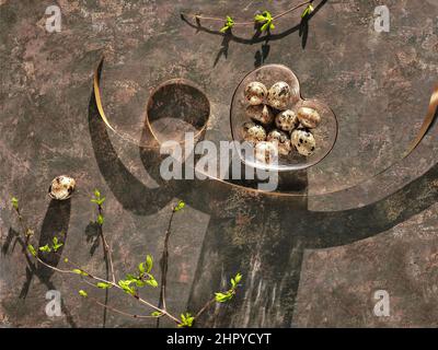 Spring Easter background with fresh leaves on twigs. Quail eggs in heart glass bowl on dark brown. Stock Photo