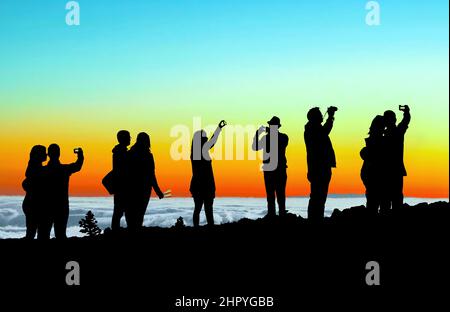 Silhouette of tourists watching above the clouds of the beautiful sunset at Volcano Teide Tenerife Stock Photo
