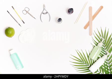 Nail care. Flat lay manicure or pedicure tools on white table with green leaves. Stock Photo