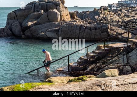 Dun Laoghaire, Ireland. 24th Feb, 2022. Despite gale force winds, a swimmer goes for a dip in the Forty Foot in Dun Laoghaire. Met Éireann has forecast wintry showers for the rest of the day. Credit: AG News/Alamy Live News Stock Photo