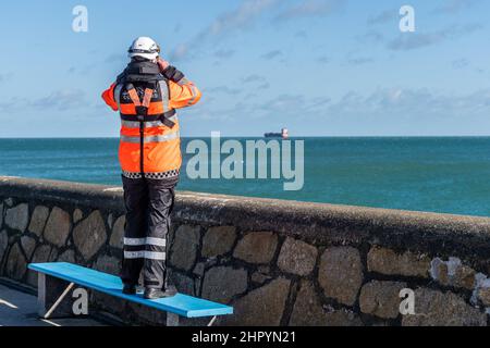 Dun Laoghaire, Ireland. 24th Feb, 2022. A member of the Irish Coastguard scans the sea from Dun Laoghaire Harbour, searching for a missing person. Credit: AG News/Alamy Live News Stock Photo