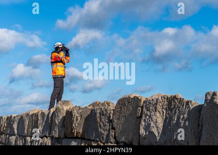 Dun Laoghaire, Ireland. 24th Feb, 2022. A member of the Irish Coastguard scans the sea from Dun Laoghaire Harbour, searching for a missing person. Credit: AG News/Alamy Live News Stock Photo