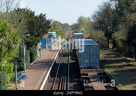 Freight train passing through Trimley railway station on route to the port of Felixstowe Suffolk UK Stock Photo