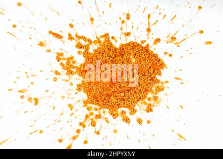 Spaghetti rings in tomato sauce splattered on a white background Stock Photo