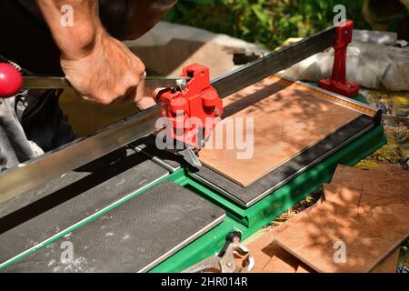 The tiler cuts the tile using a masonry cutter Stock Photo