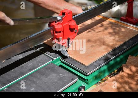 The mason cuts the tile by hand using a cutter Stock Photo