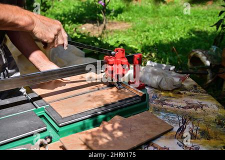 The mason cuts the tile by hand using a cutter Stock Photo
