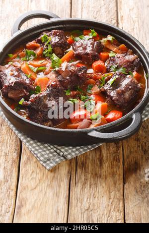 Spanish Bull Tail Stew Rabo De Toro closeup on a pot on the wooden table. Vertical Stock Photo