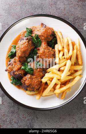 Spanish Bull Tail Stew Rabo De Toro served with french fry closeup in the plate on the table. Vertical top view from above Stock Photo