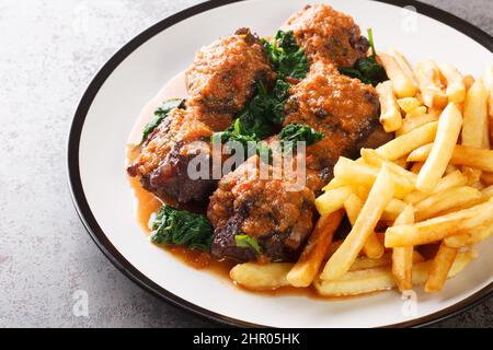 Tasty Rabo de toro or oxtail stew served with french fries on white plate on the concrete table. Horizontal Stock Photo