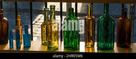 Old coloured bottles on shelf in antique shop Stock Photo
