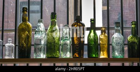 Old coloured bottles on shelf in antique shop Stock Photo