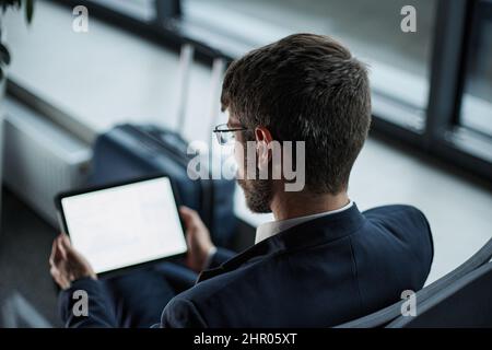thoughtful businessman with a digital tablet waiting for his fli Stock Photo