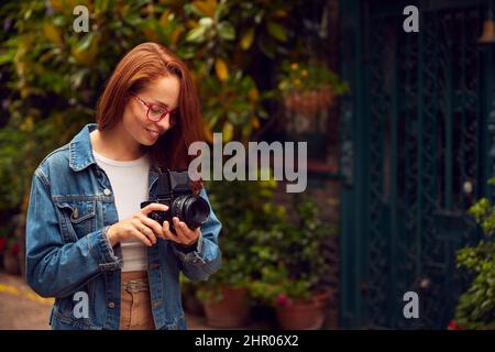 Young Woman In City Taking Photo On Retro Medium Format Film Camera To Post To Social Media Stock Photo