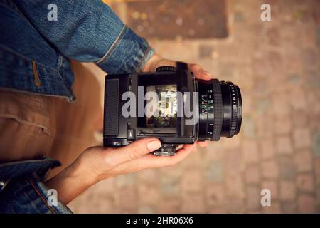 Close Up Of Woman In City Taking Photo On Retro Medium Format Film Camera To Post To Social Media Stock Photo