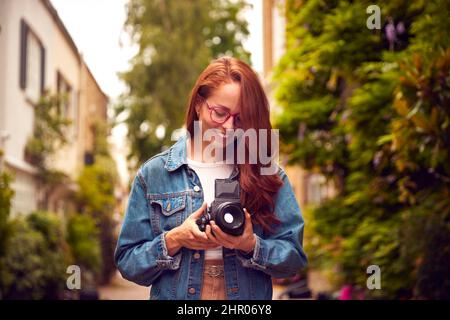 Young Woman In City Taking Photo On Retro Medium Format Film Camera To Post To Social Media Stock Photo