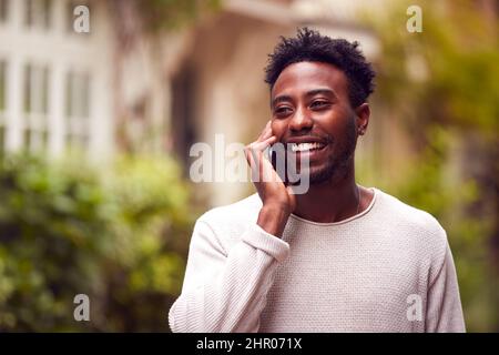 Male Vlogger Travelling Through City Talking On Mobile Phone Stock Photo