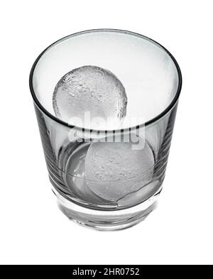 High contrast view of a clear glass with two round ice cubes isolated on white background Stock Photo