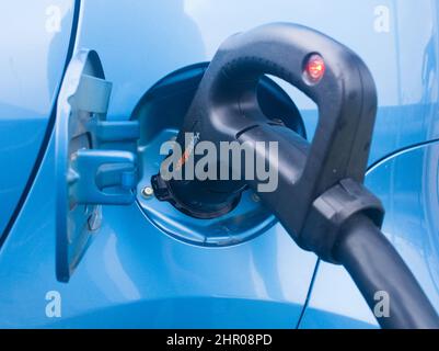 Close up of a ChaDeMo charging nozzle inserted into blue electric vehicle recharging using an InstaVolt rapid charger Stock Photo