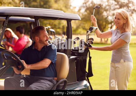 Mature And Mid Adult Couples In Buggies Playing Round On Golf Together Stock Photo