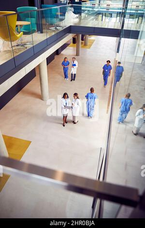 Overhead Shot Of Two Female Medical Staff In White Coats Discussing Patient Scan In Busy Hospital Stock Photo