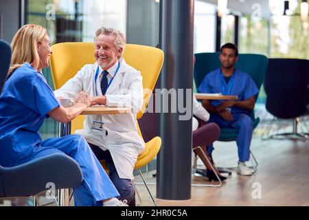Two Medical Staff In White Coat And Scrubs Taking A Break In Hospital Cafeteria Stock Photo