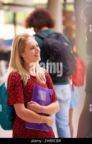 Smiling Female Student In Busy University Or College Building Stock Photo
